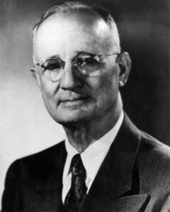 Uma imagem de Napoleon Hill de óculos e terno escuro